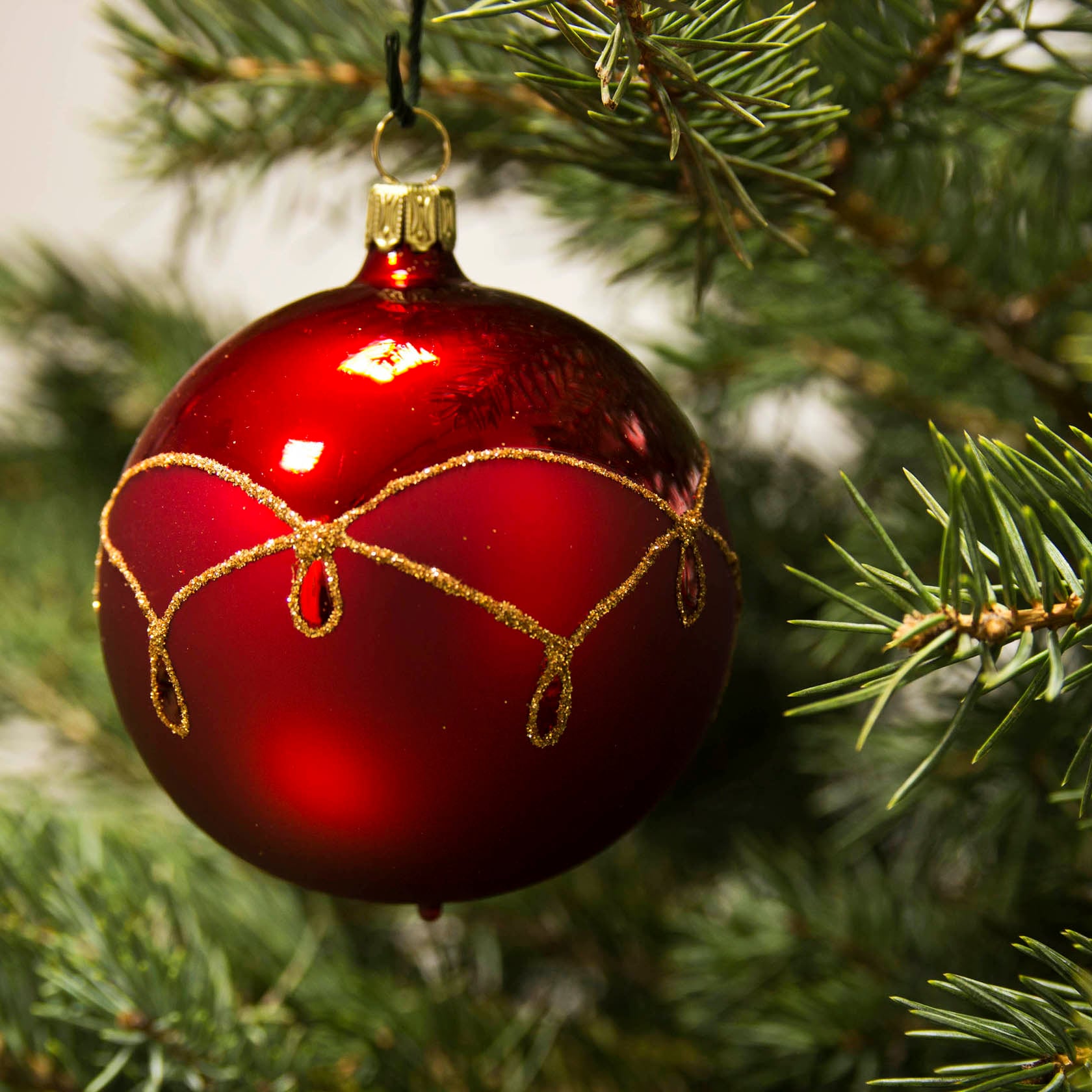 Deep Red Glass Ornament with Elegant Gold Pattern on Tree Branch Deep Red Glass Ornament with Elegant Gold Pattern on Tree Branch — Red and Gold Christmas Tree