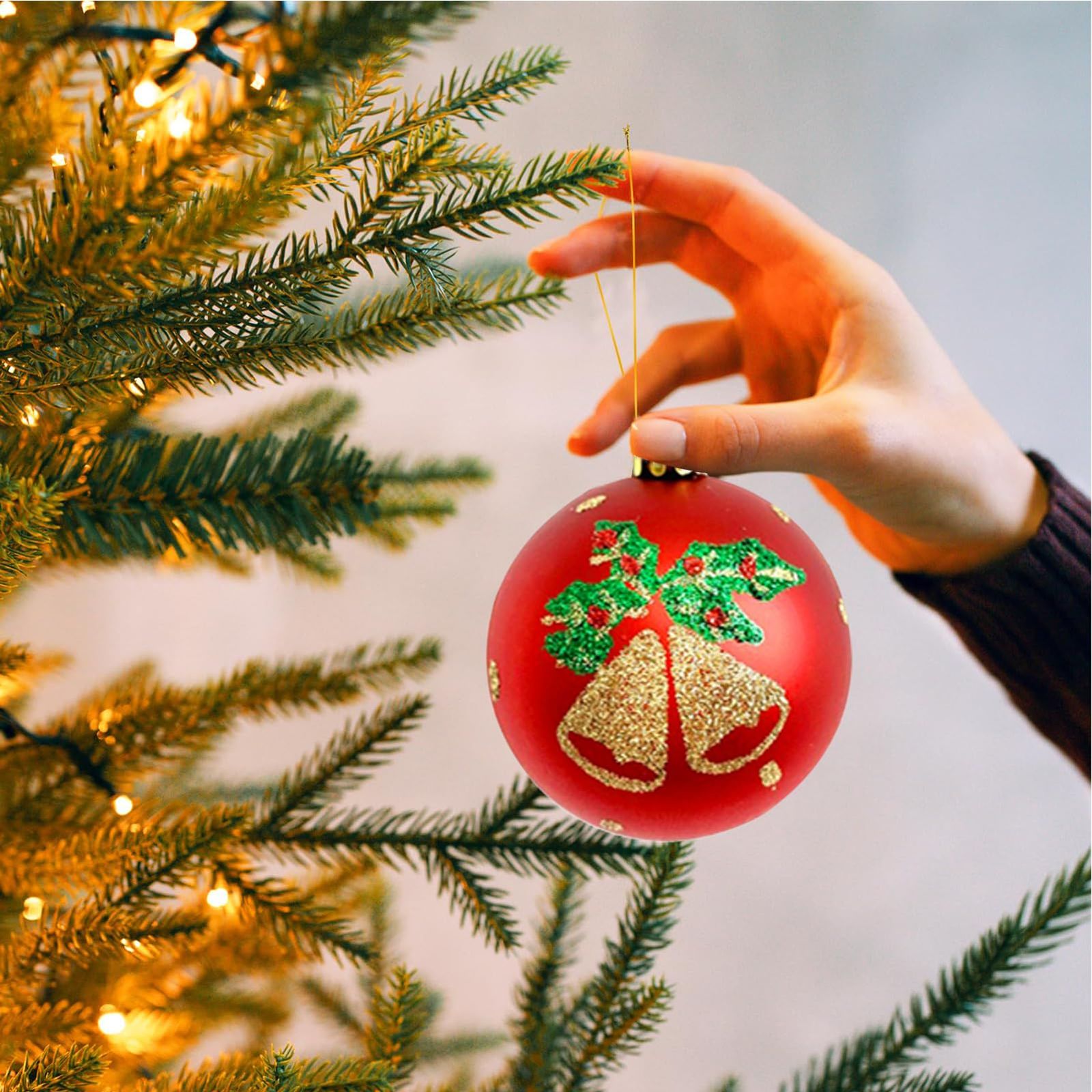 Hand Holding a Red Christmas Bauble with Green Holly Detail Hand Holding a Red Christmas Bauble with Green Holly Detail — Red and Green Christmas Tree