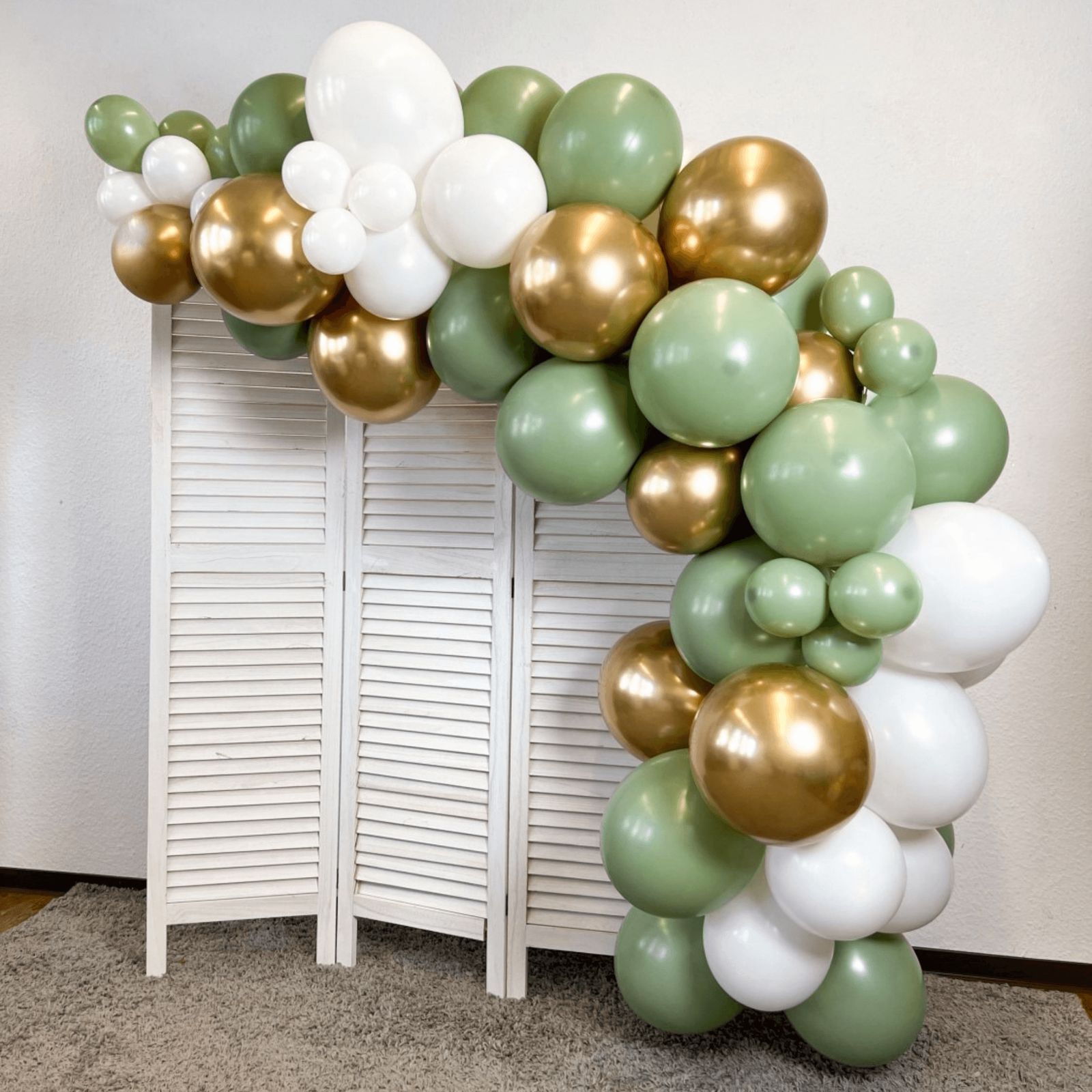 Sage Green, Gold, and White Balloon Garland Over Folding Screen — New Years Eve Balloon Garland