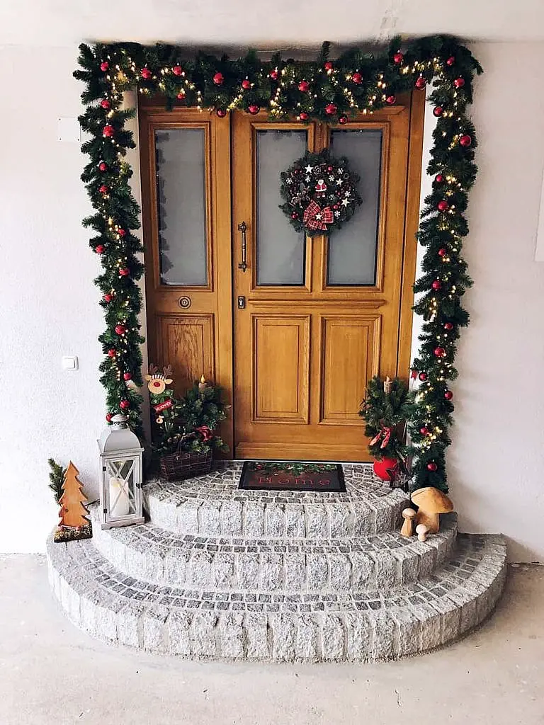 Wooden Door Framed by Pine Garland and Decorated Steps — Winter Front Door Decor