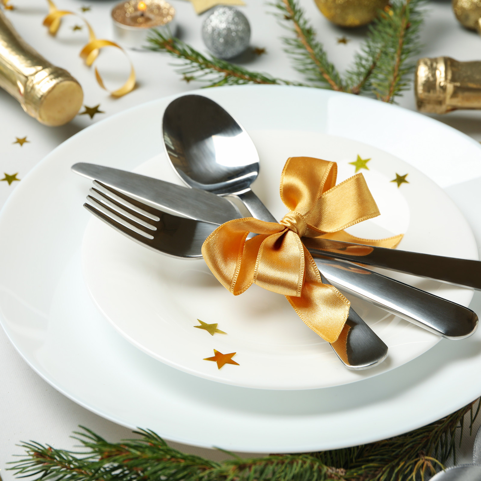 Elegant White Place Setting with Gold Ribbon-Tied Cutlery and Pine Elegant White Place Setting with Gold Ribbon-Tied Cutlery and Pine — New Years Eve Table Decor