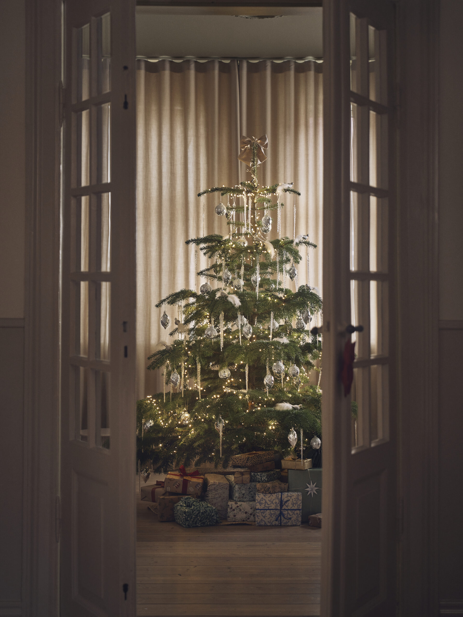 Decorated Christmas Tree with Icicle Ornaments Through Double Doors Decorated Christmas Tree with Icicle Ornaments Through Double Doors — Rustic Christmas Tree